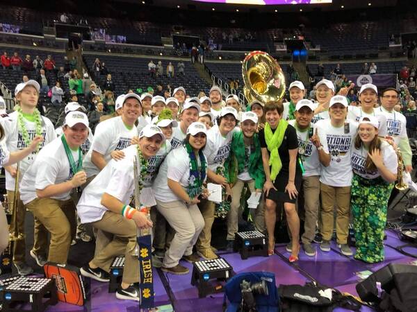 One of the ND Varsity Bands, specifically the Basketball Band, poses with ND Women's Basketball Head Coach Muffet McGraw on the court following the team's 2018 National Championship win