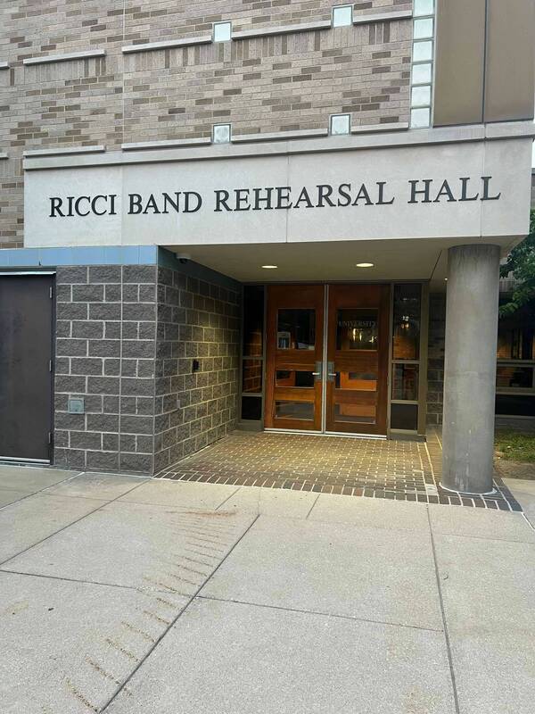 Entrance to Ricci Band Rehearsal Hall at the University of Notre Dame, featuring gray brick, wood double doors, and a gray concrete column.